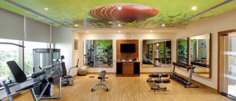 A gym with exercise equipment, a bench, and a television.