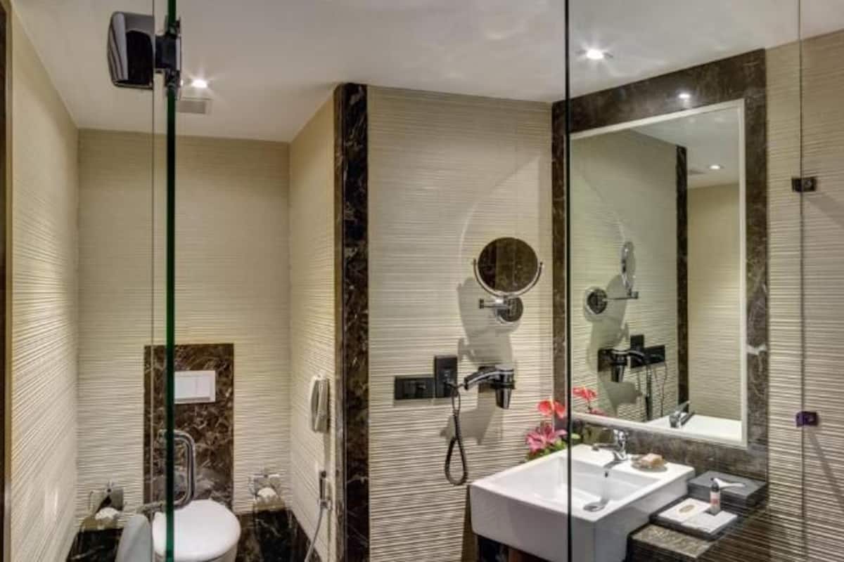 A modern bathroom with a glass shower enclosure, a large mirror, and a vanity with a sink and mirror.