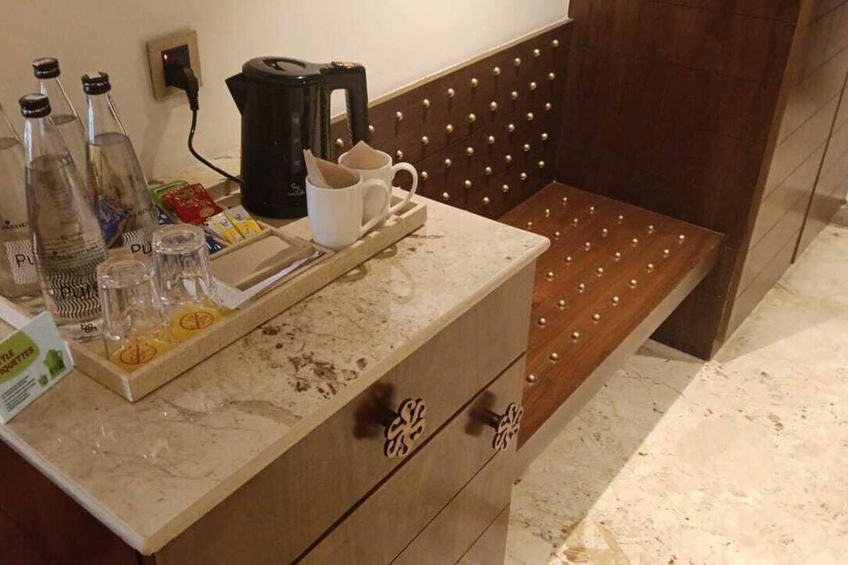 A hotel reception area with a marble counter, several bottles, a coffee maker, and a tray with items.
