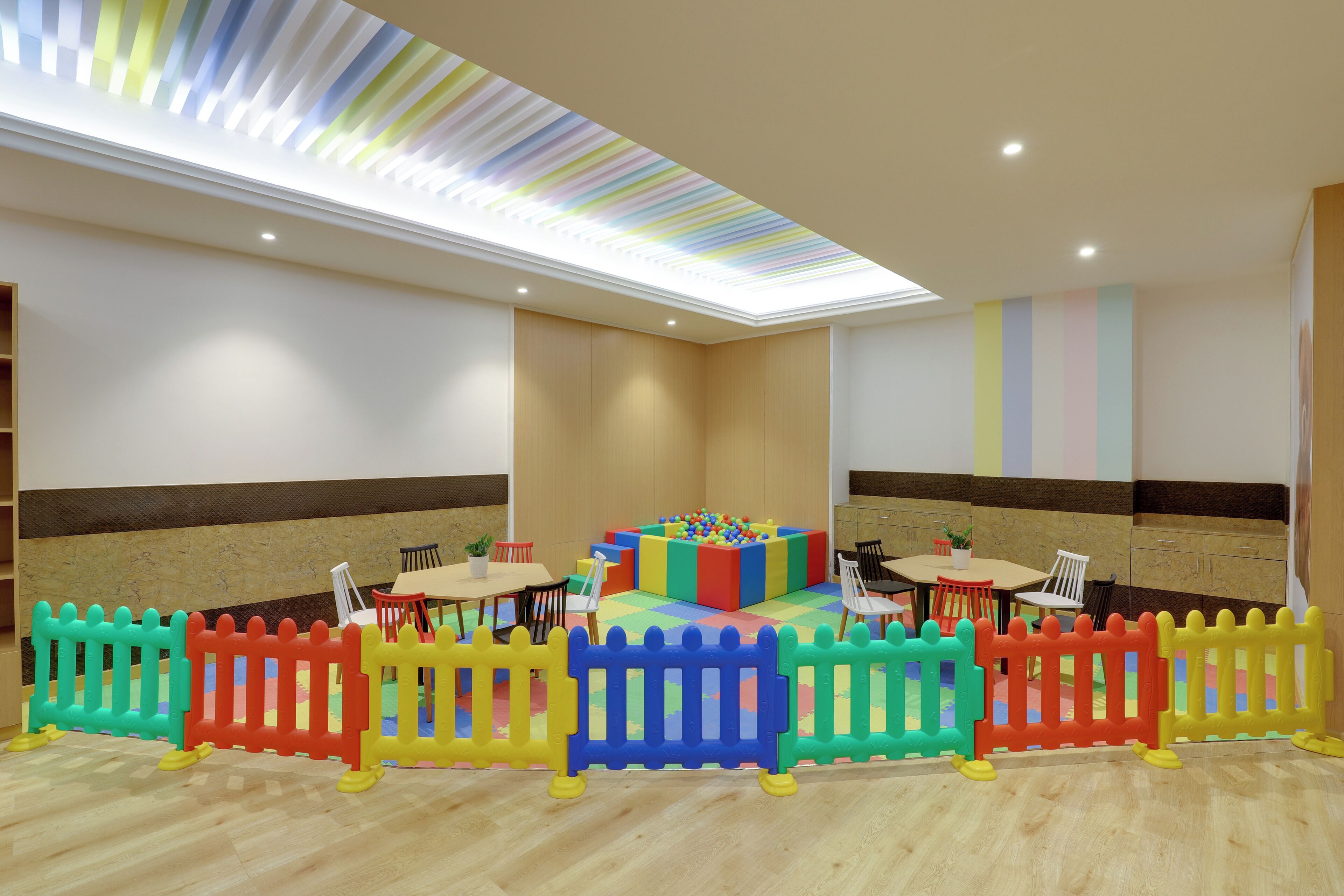 A children's play area with colorful play structures, seating, and a soft play floor.