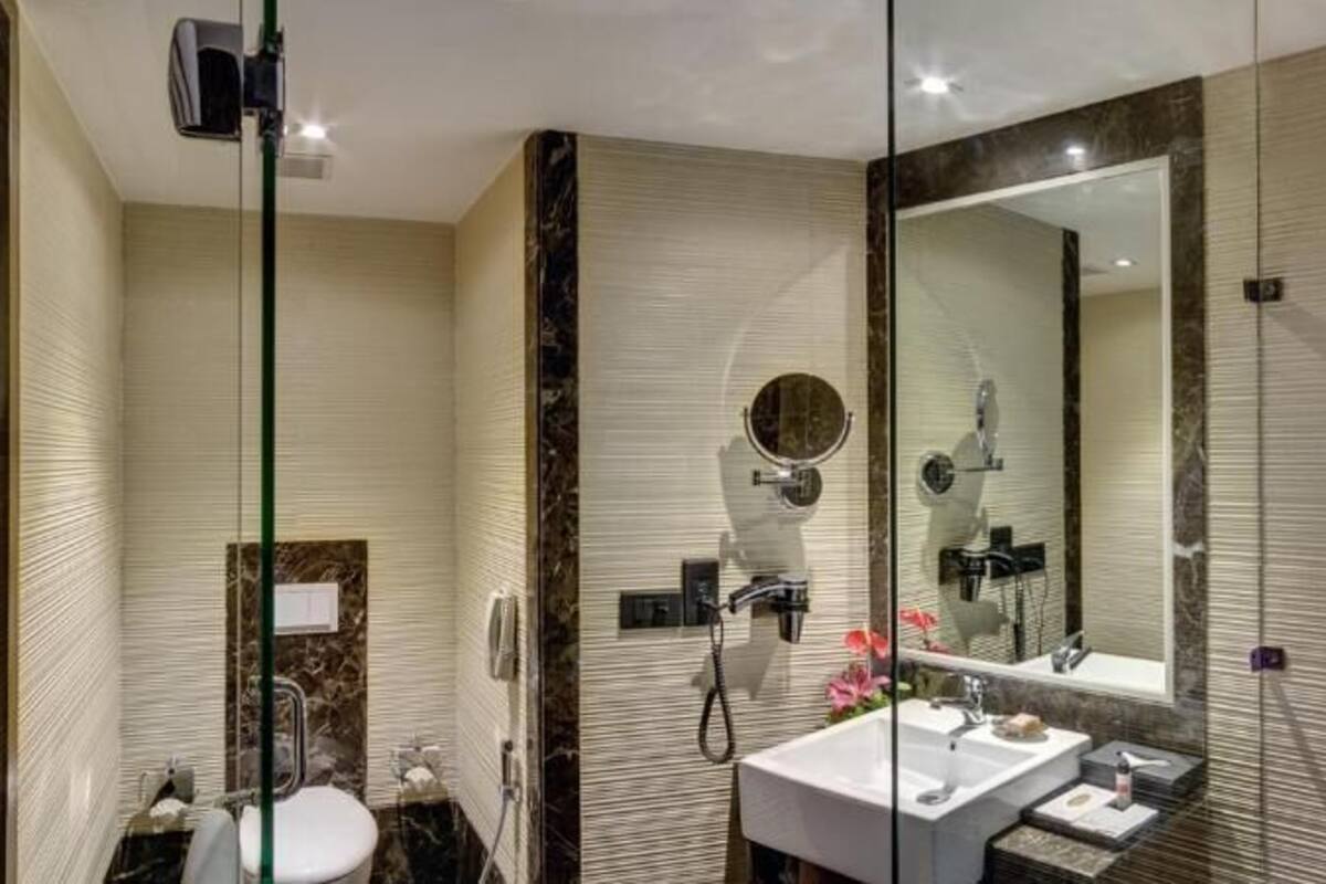A modern bathroom with a glass shower enclosure, a large mirror, and a vanity with a sink and mirror.