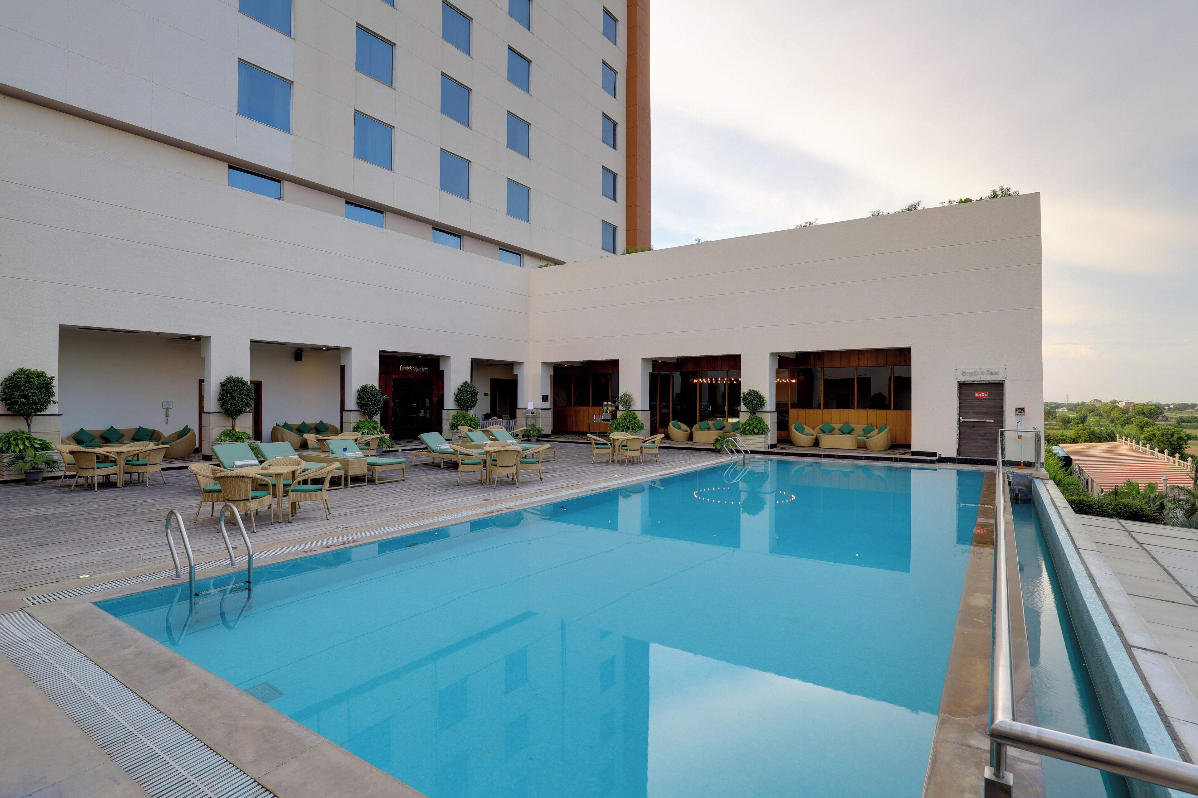 A swimming pool with lounge chairs and a building with multiple floors and windows.