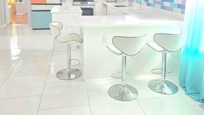 Una cocina moderna con gabinetes blancos, una isla central con taburetes altos y un salpicadero de azulejos.