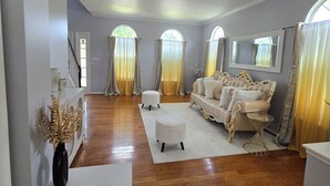 Amplia sala de estar con piso de madera, un sofá blanco y un espejo grande.