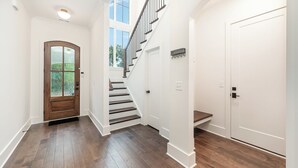 A hallway with a wooden door, a staircase, and a white door.