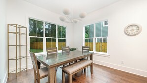 A dining room with a wooden table, chairs, a bench, and a ceiling fan.