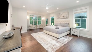 A bedroom with a large bed, bedside tables, a desk, and a chair.