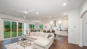 A spacious living room with a large sectional sofa, a coffee table, and a dining area in the background.