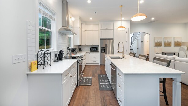 A modern kitchen with white cabinetry, stainless steel appliances, and a central island.