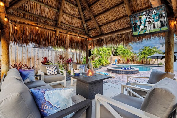 An outdoor patio with a thatched roof, a pool, and outdoor seating. - Walk2BEACH|HeatedPool|Spa|GamingRoom|Tikihut|Cove (deerfield beach)