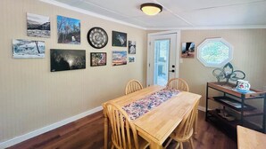 Un comedor con una mesa y sillas de madera, rodeado de paredes decoradas con varias fotos enmarcadas.