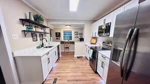 Una cocina moderna con armarios blancos, electrodomésticos de acero inoxidable y piso de madera.
