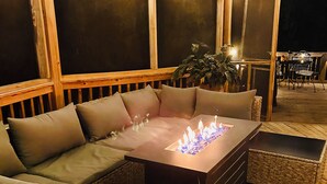 Un espacio al aire libre con asientos acolchados, una chimenea y una terraza de madera.