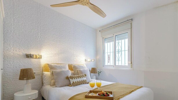 Une chambre à coucher avec un lit, des lampes de chevet, une fenêtre et un plateau contenant de la nourriture et des boissons.