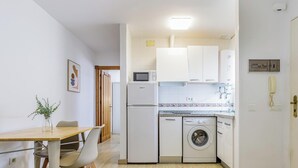Une cuisine compacte équipée d’un four à micro-ondes, d’un réfrigérateur et d’un lave-linge.