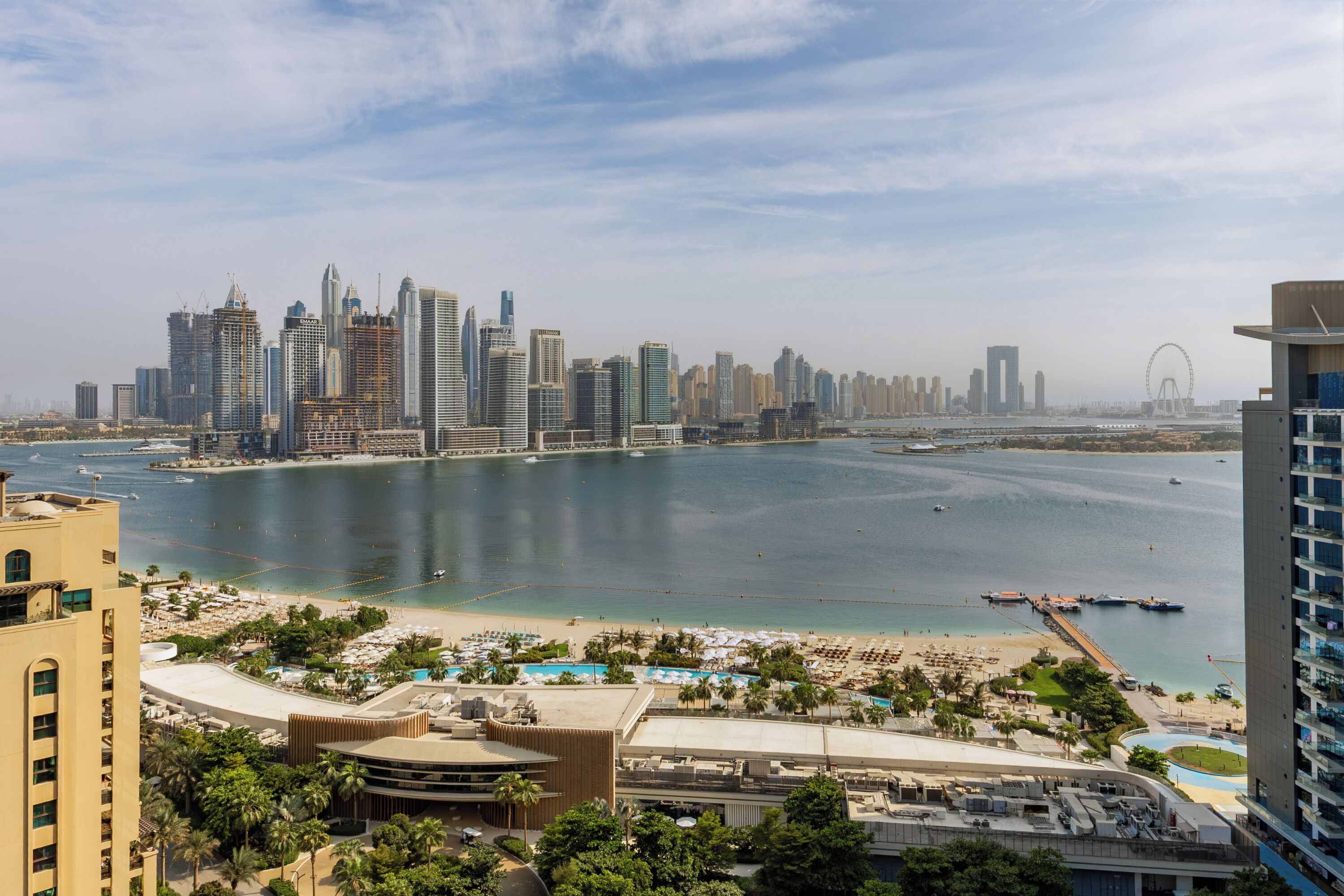 A coastal cityscape with high-rise buildings, a beach, and a marina.