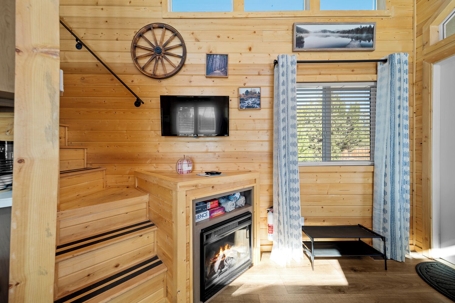 Interno di una baita in legno con camino, televisione e finestra con tende.