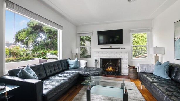 A modern living room with a fireplace, leather sofas, and a large TV. - Bird Rock, La Jolla Whitewater w/AC (La Jolla)
