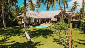 Ein Resort mit Pool, strohgedeckten Gebäuden und Palmen.