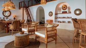 Ein geräumiges Zimmer mit Korbmöbeln, einer Treppe und dekorativer Wandkunst.