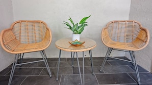A corner with two wicker chairs and a small round table with a potted plant.