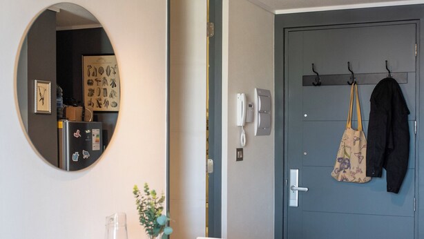 Un coin repas avec une table dressée pour deux personnes, un miroir et une porte avec un porte-manteau.