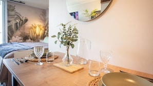 Une table de petit-déjeuner soigneusement dressée, agrémentée d’un vase de verdure, d’une carafe et de plusieurs verres.