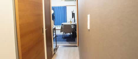 Un corridoio stretto con porte in legno su un lato e una tenda blu sullo sfondo.