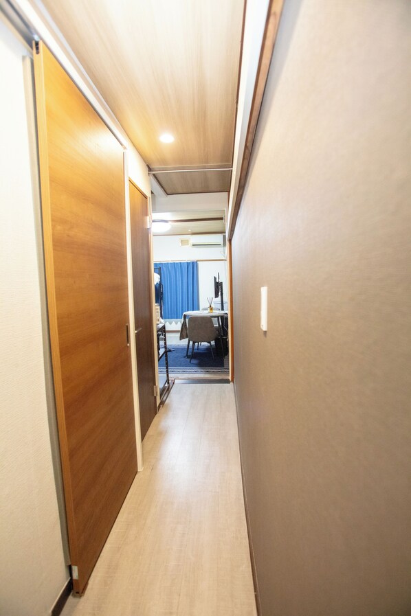 A narrow hallway with wooden doors on one side and a blue curtain in the background.