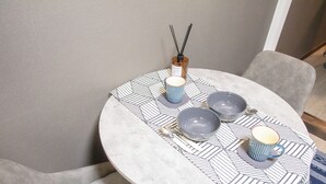 A round dining table with a patterned tablecloth, two striped cups, two gray bowls, a spoon, and a candle with reed diffusers. - Full-rental, ideal for short- to medium-term stays for sightseeing, business trips, study abroad, etc./Apartment in Amakubo, Tsukuba City (Tsukuba City Amakubo 4chome)