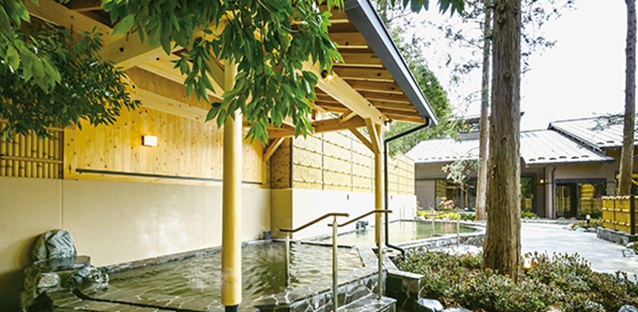 A traditional Japanese building with a stone water feature, wooden beams, and a covered walkway.