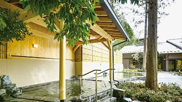 A traditional Japanese building with a stone water feature, wooden beams, and a covered walkway.