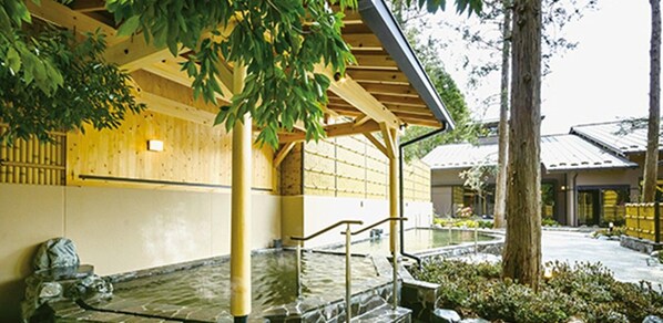 A traditional Japanese building with a stone water feature, wooden beams, and a covered walkway.