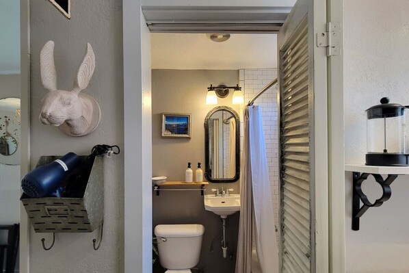 Een badkamer met toilet, wastafel en spiegel. Er is een douchegordijn en een wandradiator.