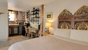 A room with a bed, a desk with a chair, a lamp, and a decorative headboard.