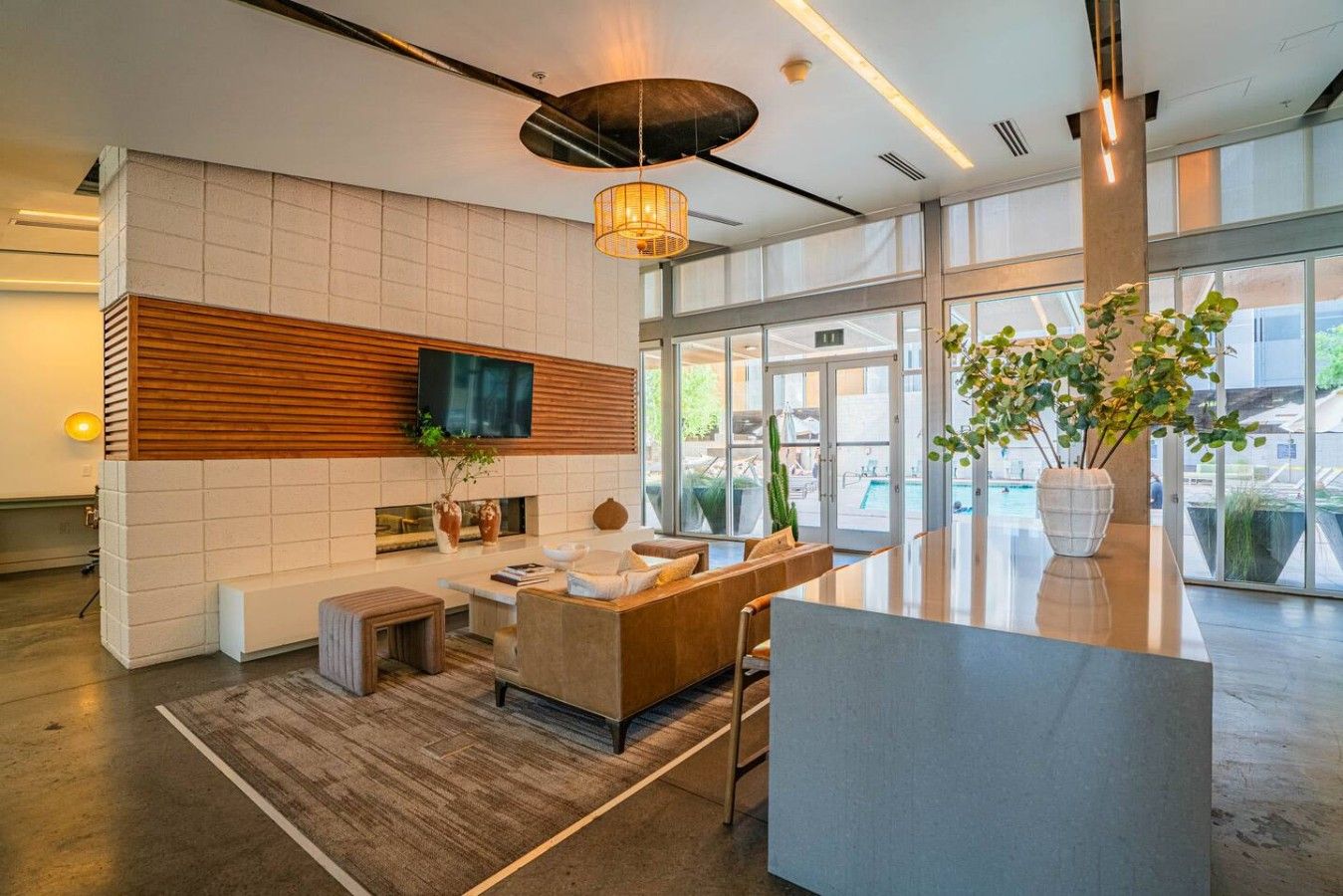 A modern lobby with a seating area, a flat-screen TV, a large window, and a plant.