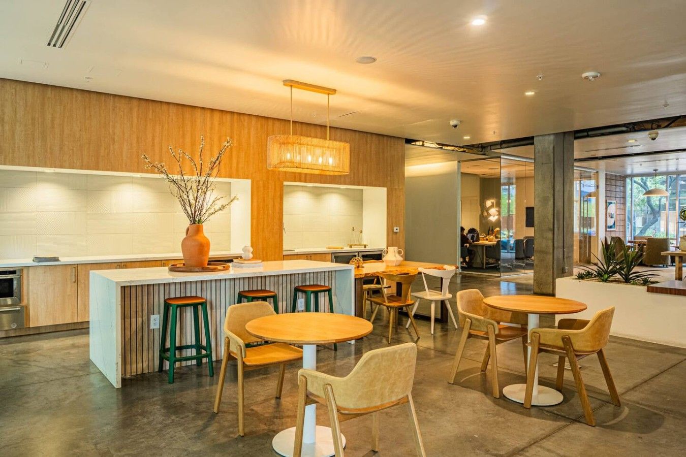 Decoração moderna com um bar central, diferentes opções de assentos e vista para o exterior através de grandes janelas.