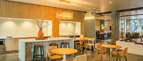 Decoração moderna com um bar central, diferentes opções de assentos e vista para o exterior através de grandes janelas.