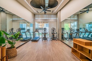 A gym with treadmills, elliptical machines, and a ceiling fan.