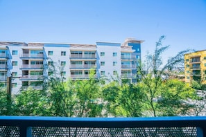 En flervåningsbostadsbyggnad med balkonger, omgiven av grönska.