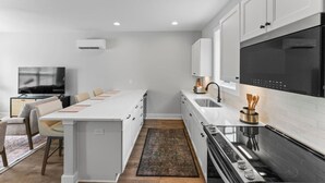 A modern kitchen with white cabinetry, a central island, a built-in oven, and a large window. - Mountain Biking, Campus & close to downtown (Knoxville)