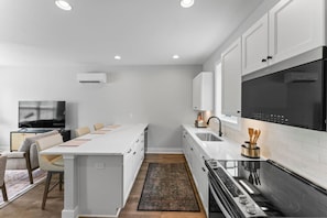 A modern kitchen with white cabinetry, a central island, a built-in oven, and a large window.