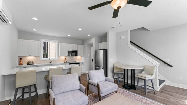 A modern kitchen with white cabinets, a central island, and a dining area with a table and chairs. - Mountain Biking, Campus & close to downtown (Knoxville)
