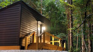 A cabin with a wooden exterior, a porch, and a staircase leading to the entrance. - Romantic Hideaway | Hot Tub Near Thunder Ridge (Omaha)