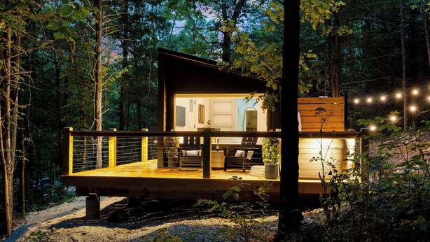 A cabin with a wooden deck, a dining area, and a large window. - Romantic Hideaway | Hot Tub Near Thunder Ridge (Omaha)