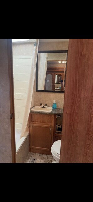 Un baño pequeño con tocador de madera, lavamanos e inodoro.