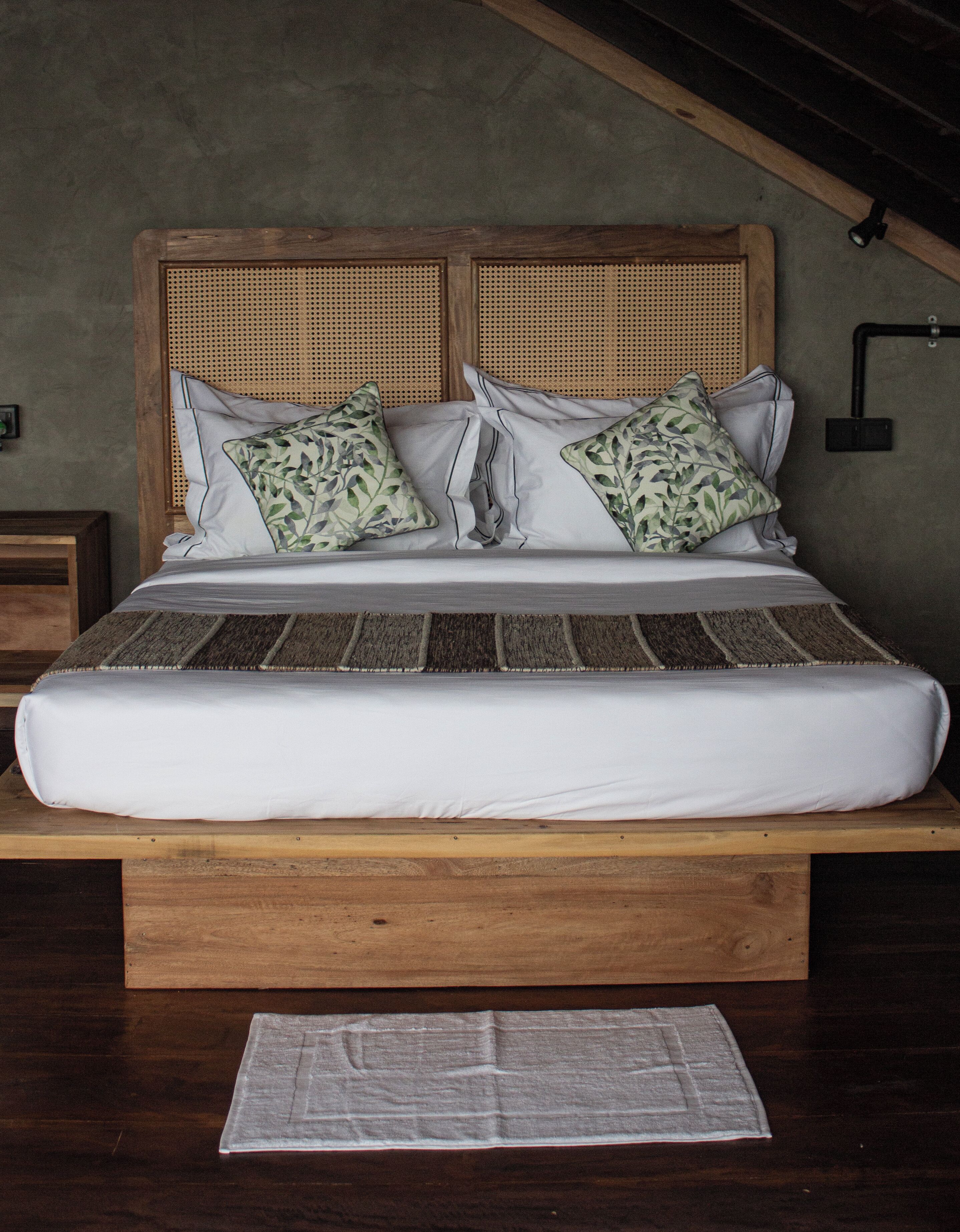 Una cama con estructura de madera, dos almohadas y un colchón blanco.