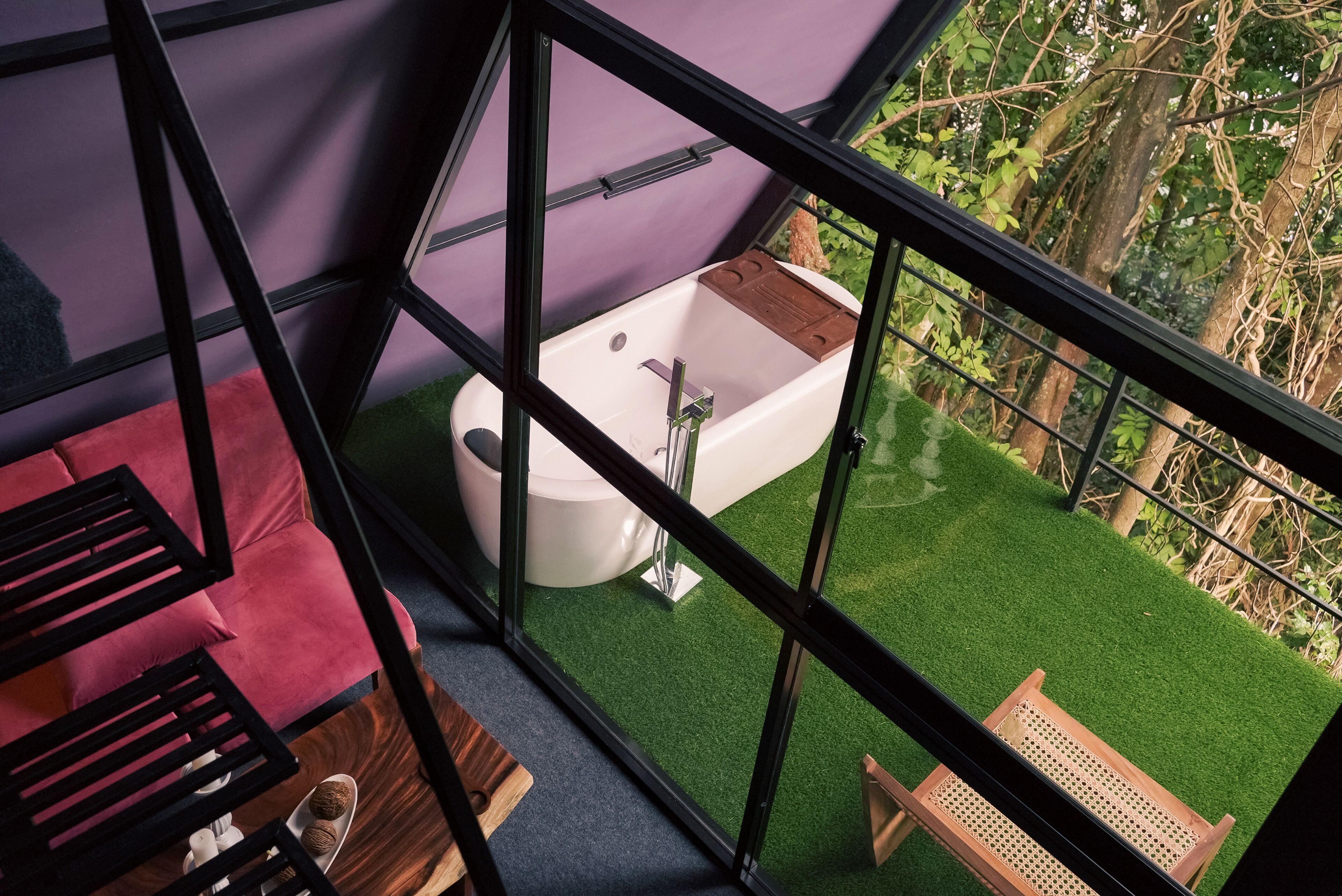 A modern bathroom with a bathtub, a red sofa, and a wooden bench.