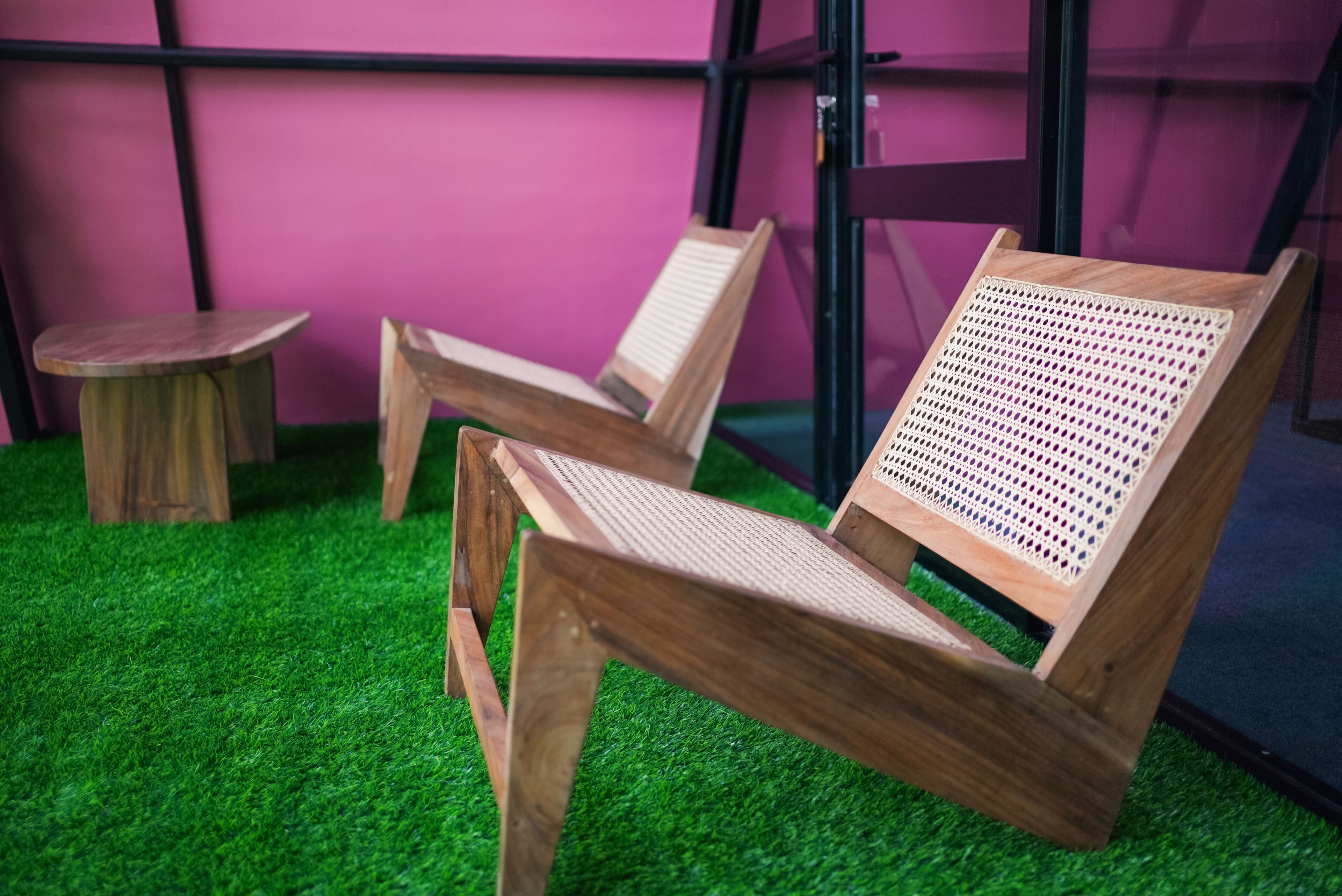 Two wooden chairs with woven seats and backs, placed on artificial green grass.