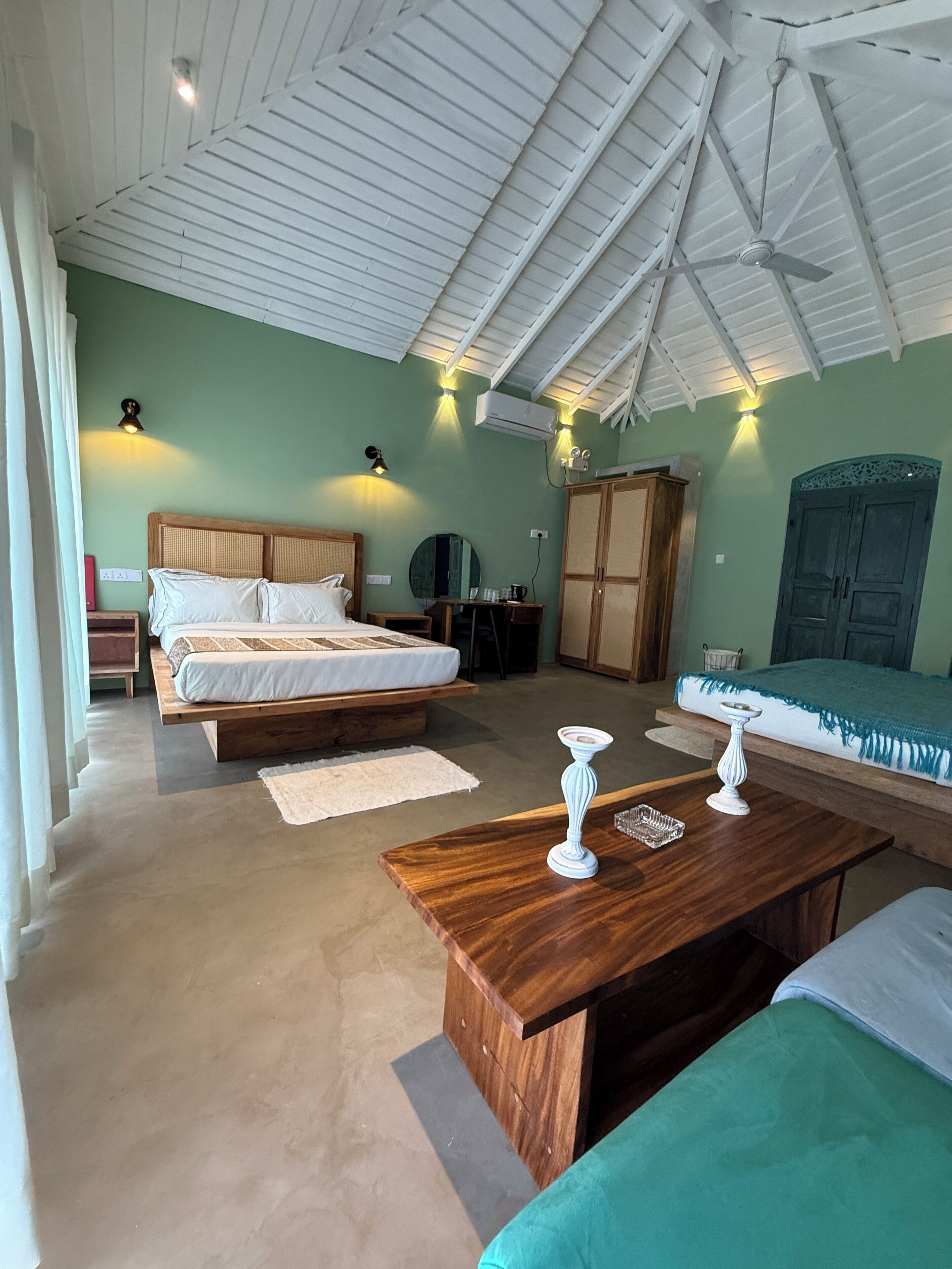 A spacious bedroom with a large bed, a wooden nightstand, a desk, and a wardrobe.